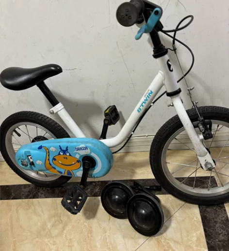 出一辆白色和蓝色的儿童自行车，品牌迪卡侬。...