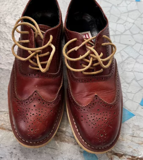 出一双棕色的真皮布洛克雕花男鞋。鞋子颜色为...