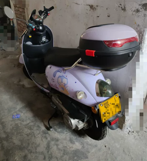 出一辆紫色踏板摩托车，车身成色很新，贴了星...